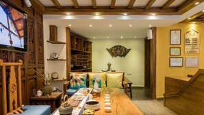 A traditional Japanese-style room with tatami flooring, a low wooden table set with tea ceremony utensils, and a television mounted on the wall.