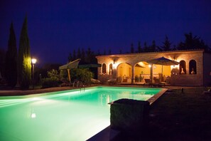 Un espace piscine avec un bâtiment en briques, des sièges extérieurs et un lampadaire.