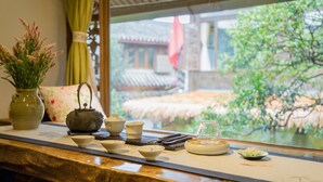 A traditional tea set on a table with a view of a garden and a building in the background. - Li Jiang Tang Feng Yard No.4 (Lijiang)