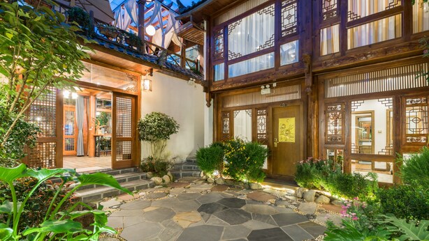 A traditional Japanese-style building with a stone courtyard, wooden gates, and a well-maintained garden. - Li Jiang Tang Feng Yard No.4 (Lijiang)