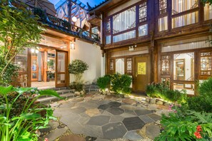 Een traditioneel Japans gebouw met een met stenen bestrate binnenplaats, houten poorten en een goed onderhouden tuin.