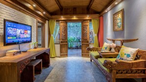 A wooden interior with a TV on a wooden desk, a sofa with cushions, and a framed picture on the wall. - Li Jiang Tang Feng Yard No.4 (Lijiang)