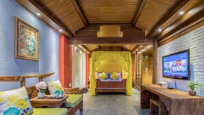 A room with a bed under a yellow canopy, a wooden bench, a TV on the wall, and a painting on the wall. - Li Jiang Tang Feng Yard No.4 (Lijiang)