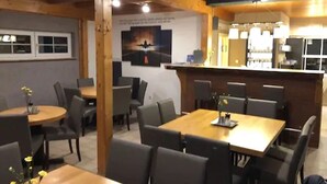 A restaurant with wooden beams, round tables, and chairs. - Pension Flying Ranch (Koelleda)