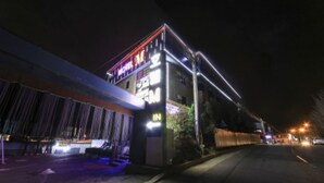 Een hotel met een neonbord, een overdekte ingang en een straatbeeld bij nacht.