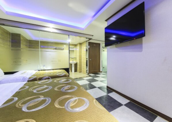 A hotel room with a bed, a TV mounted on the wall, and a checkered floor. - M Hotel (Gimpo)