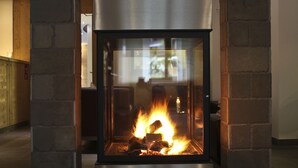 A modern fireplace with a glass front, flanked by stone pillars, and a metal chimney structure above.