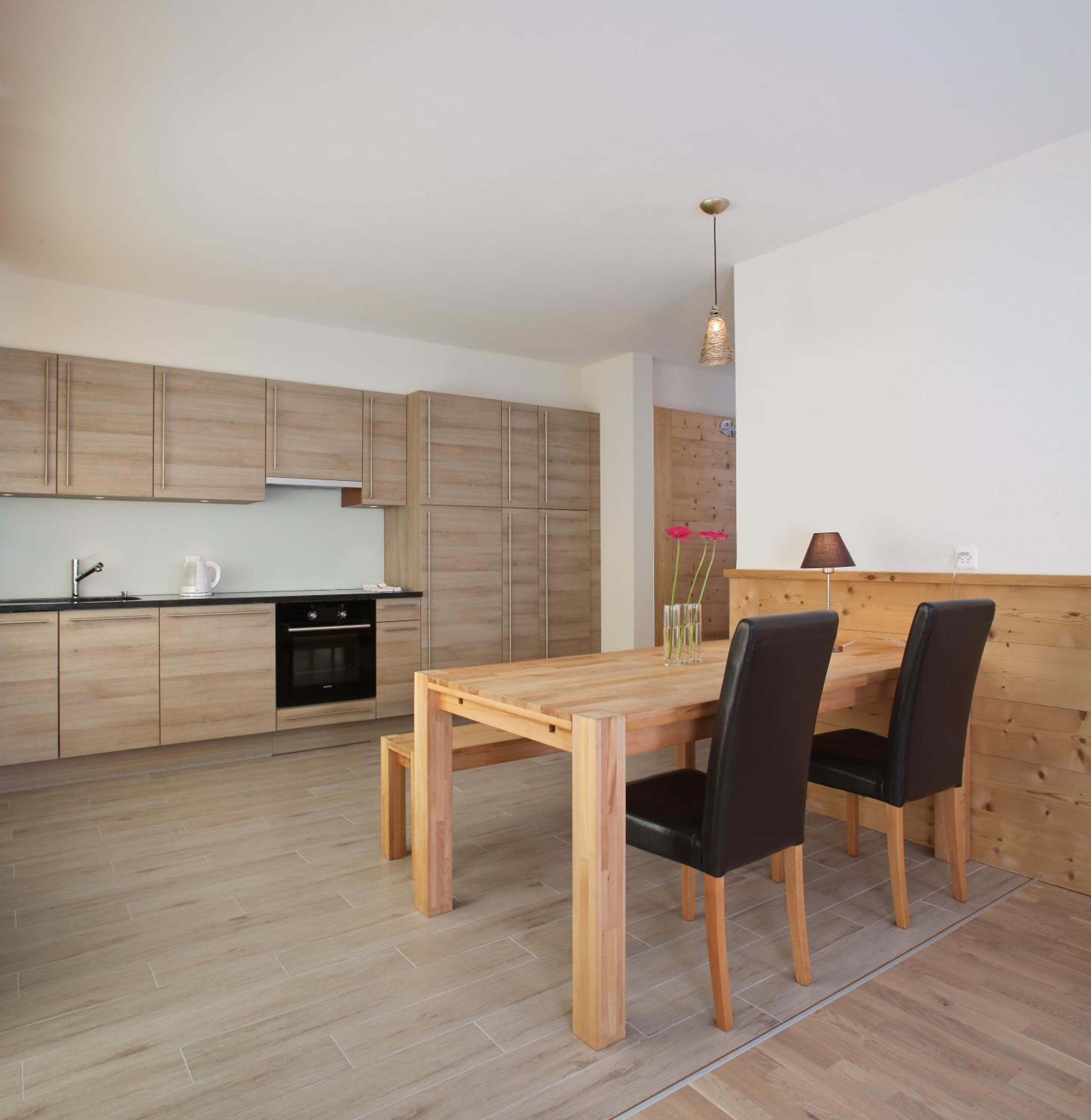 A modern kitchen with wooden cabinets and a dining area with a wooden table and chairs.