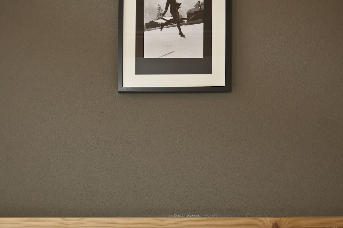 Ein Hotelzimmer mit einem hölzernen Kopfteil, zwei weißen Kissen und einem gerahmten Bild an der Wand.