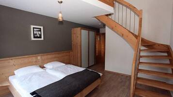 Une chambre à coucher avec un lit en bois, un escalier et un tableau encadré au mur.
