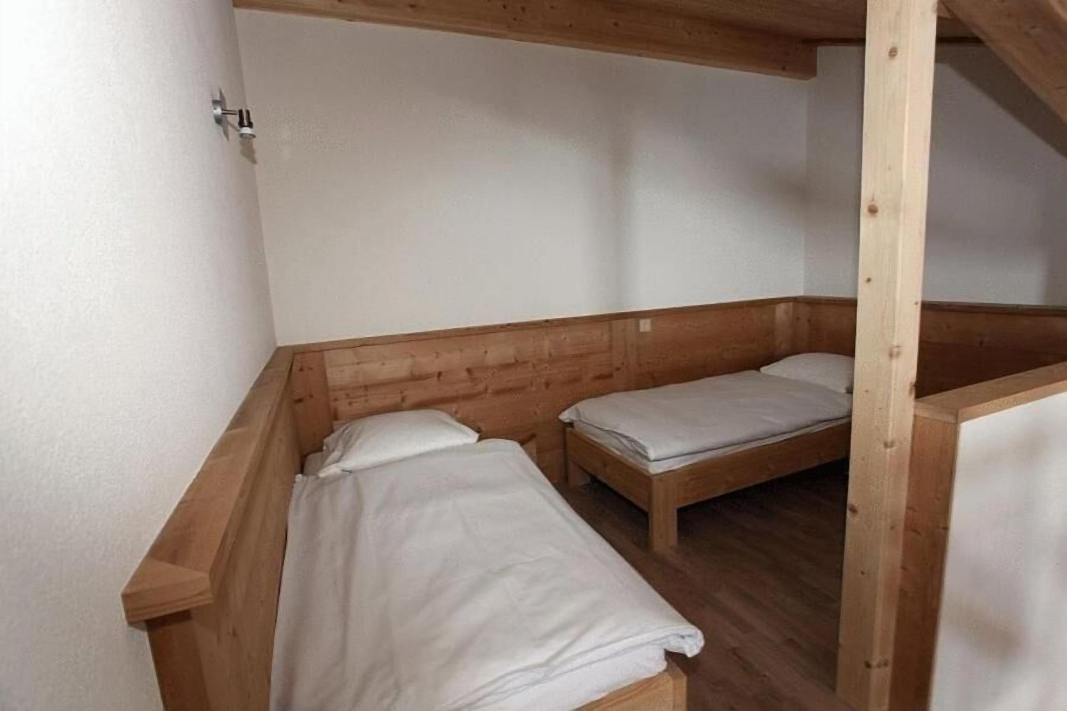Una petita habitació d'estil cabana amb dos llits individuals i una panxa de fusta.