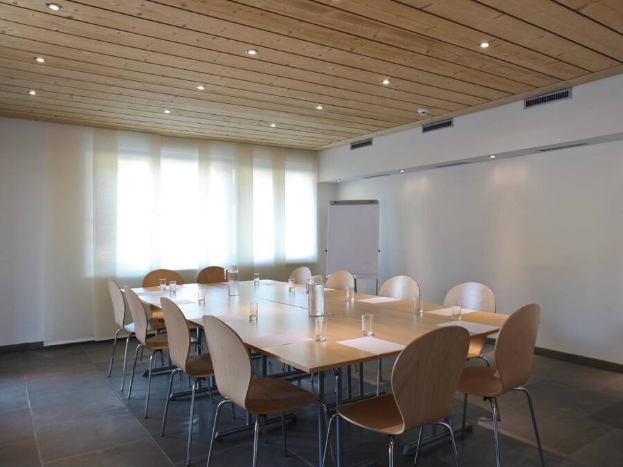 A conference room with a long table, chairs, and a whiteboard.