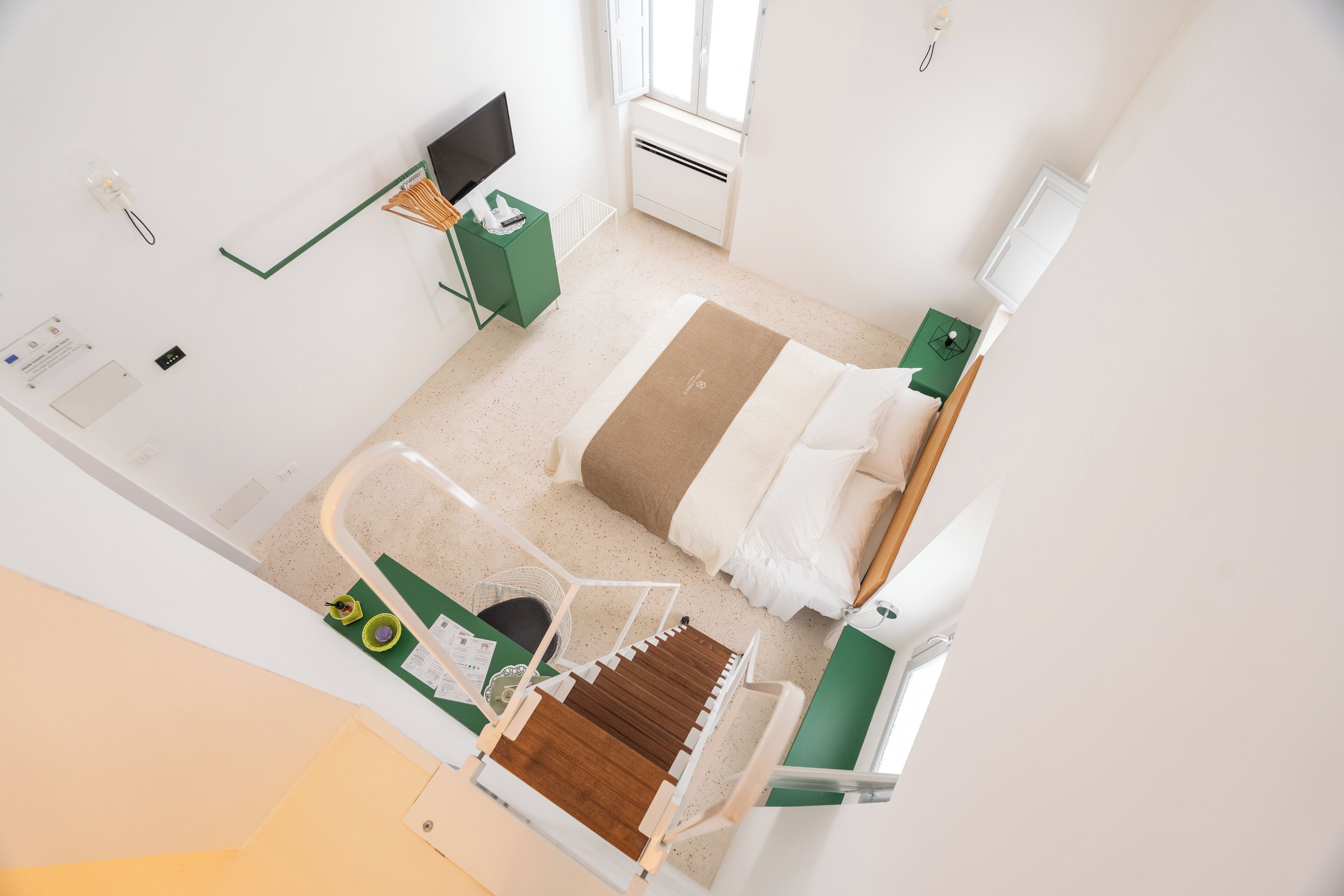 Ein modernes Hotelzimmer mit Bett, Nachttisch, Fernseher und Fenster.
