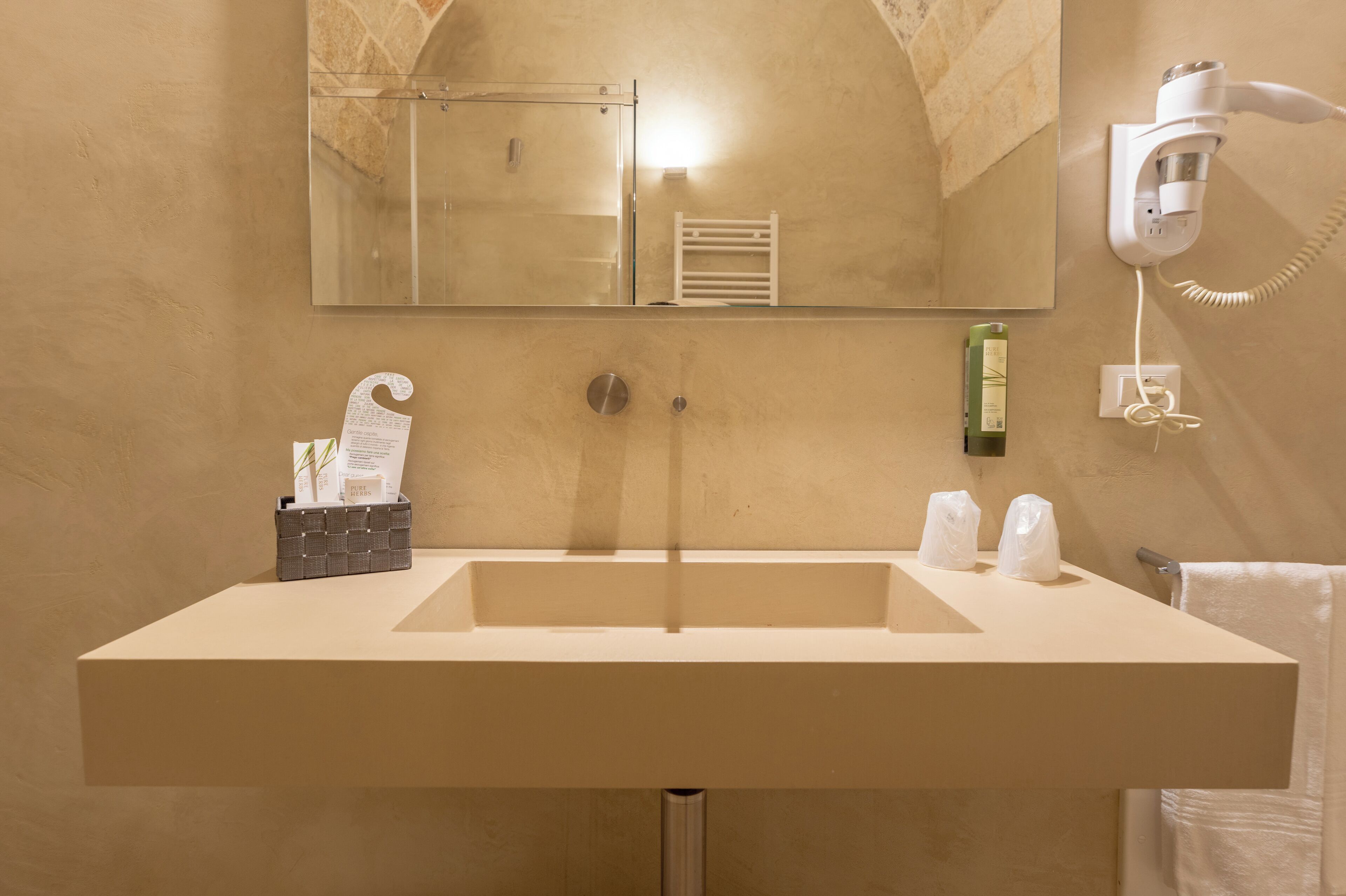 Une salle de bain avec un grand lavabo, un miroir, un sèche-cheveux et un porte-serviettes.