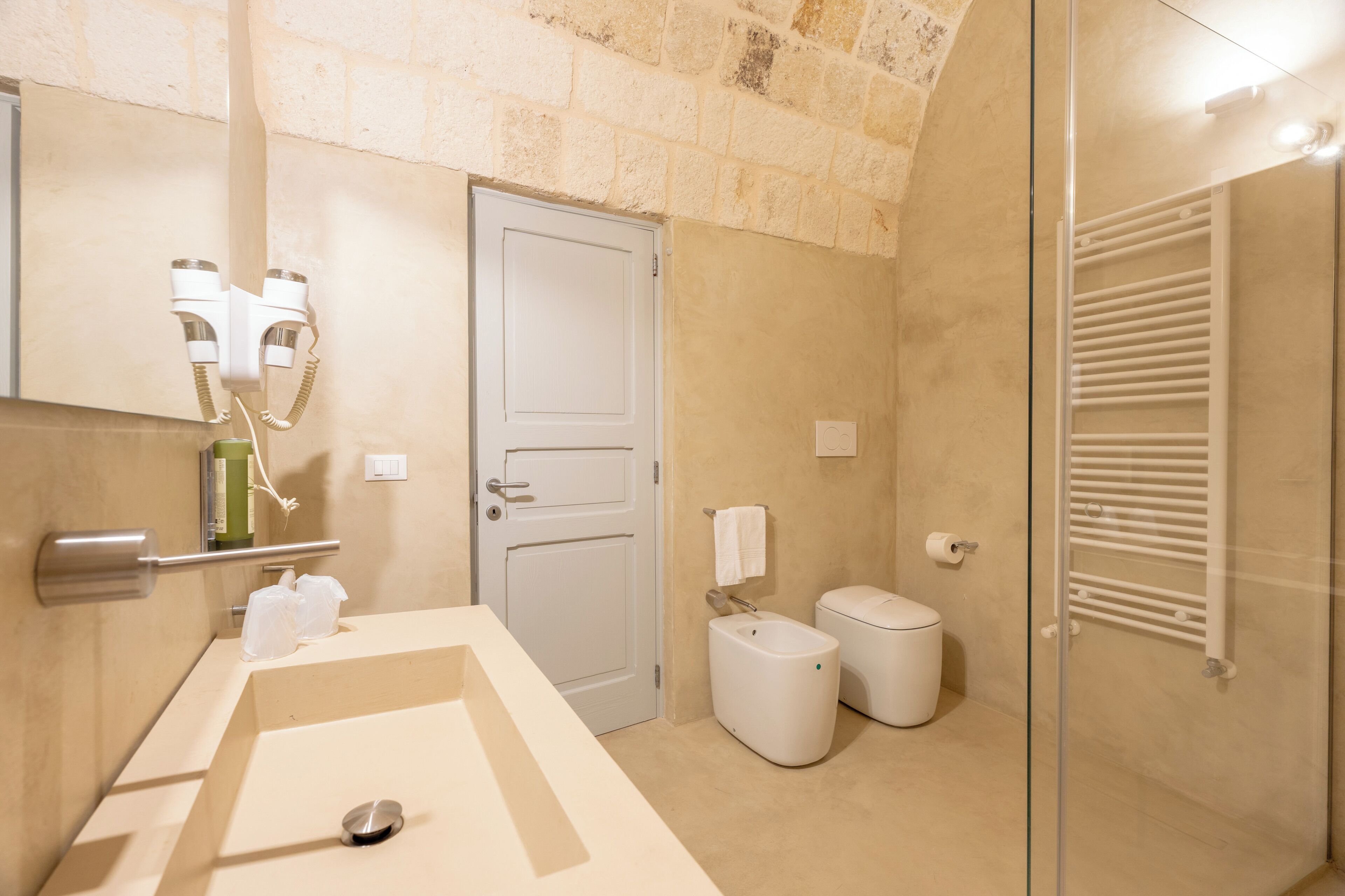 A modern bathroom with a large sink, a toilet, and a shower area.