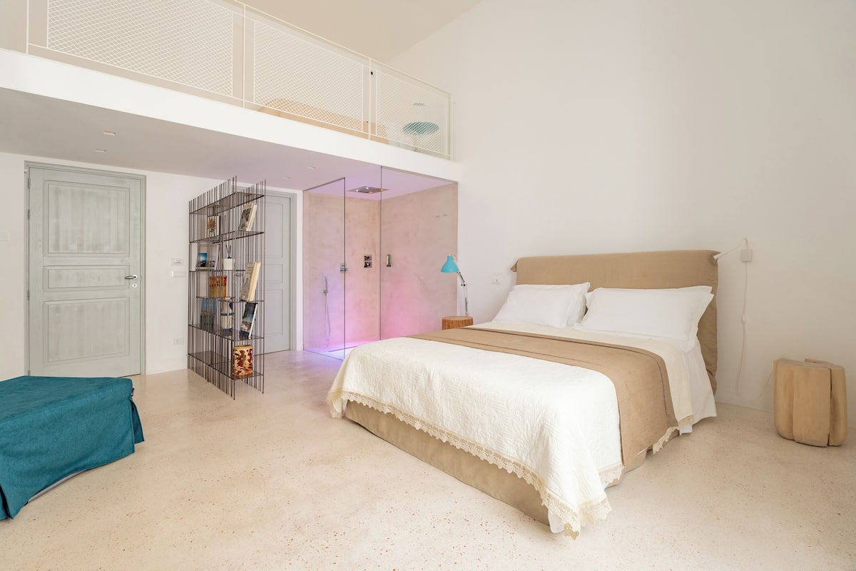 A bedroom with a bed, a bedside table, a lamp, and a wardrobe.