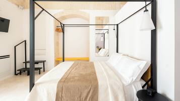 A modern bedroom with a four-poster bed, a bedside table, and a hanging lamp.