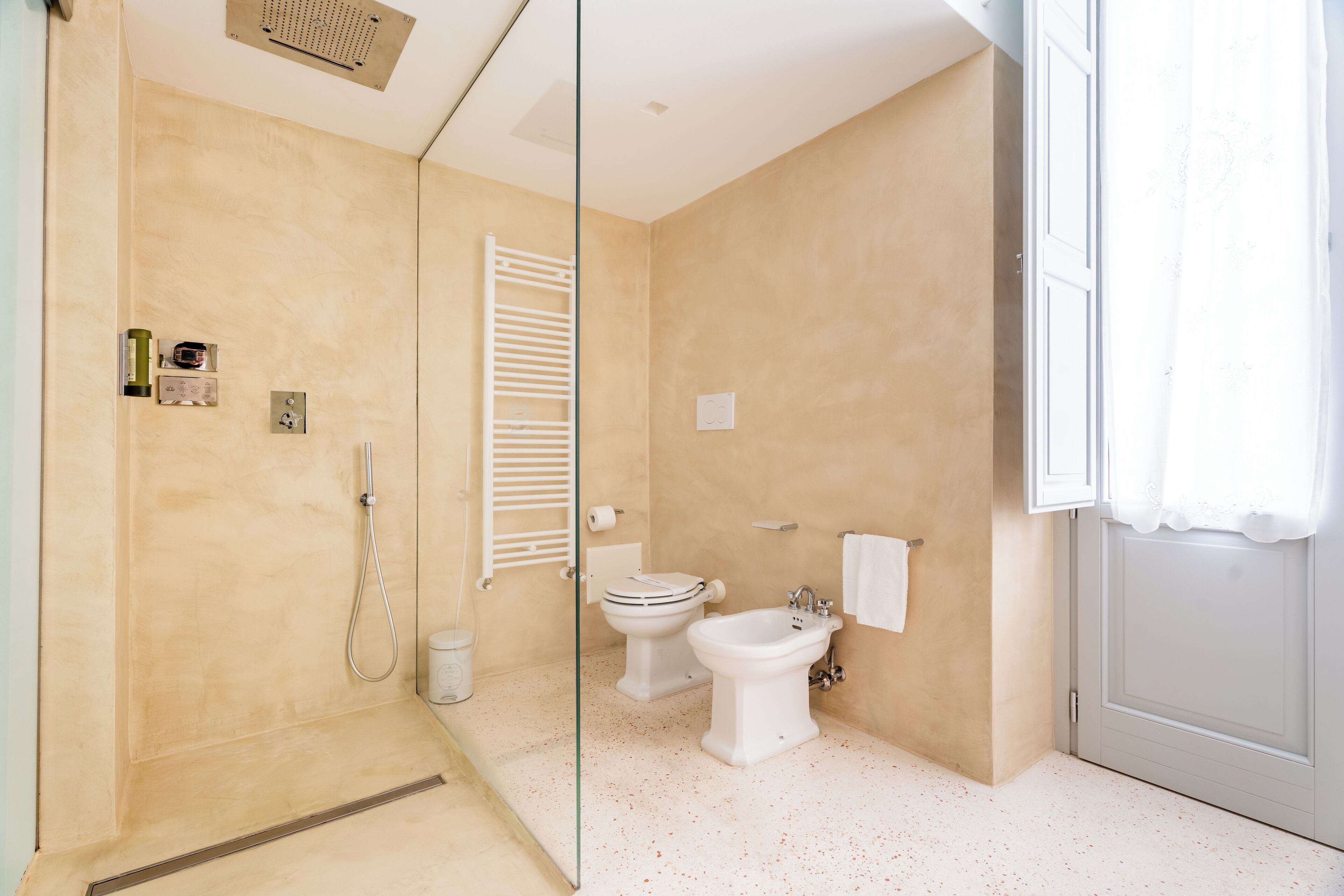 Un bany modern amb un box de dutxa de vidre, un vàter i un bidet.