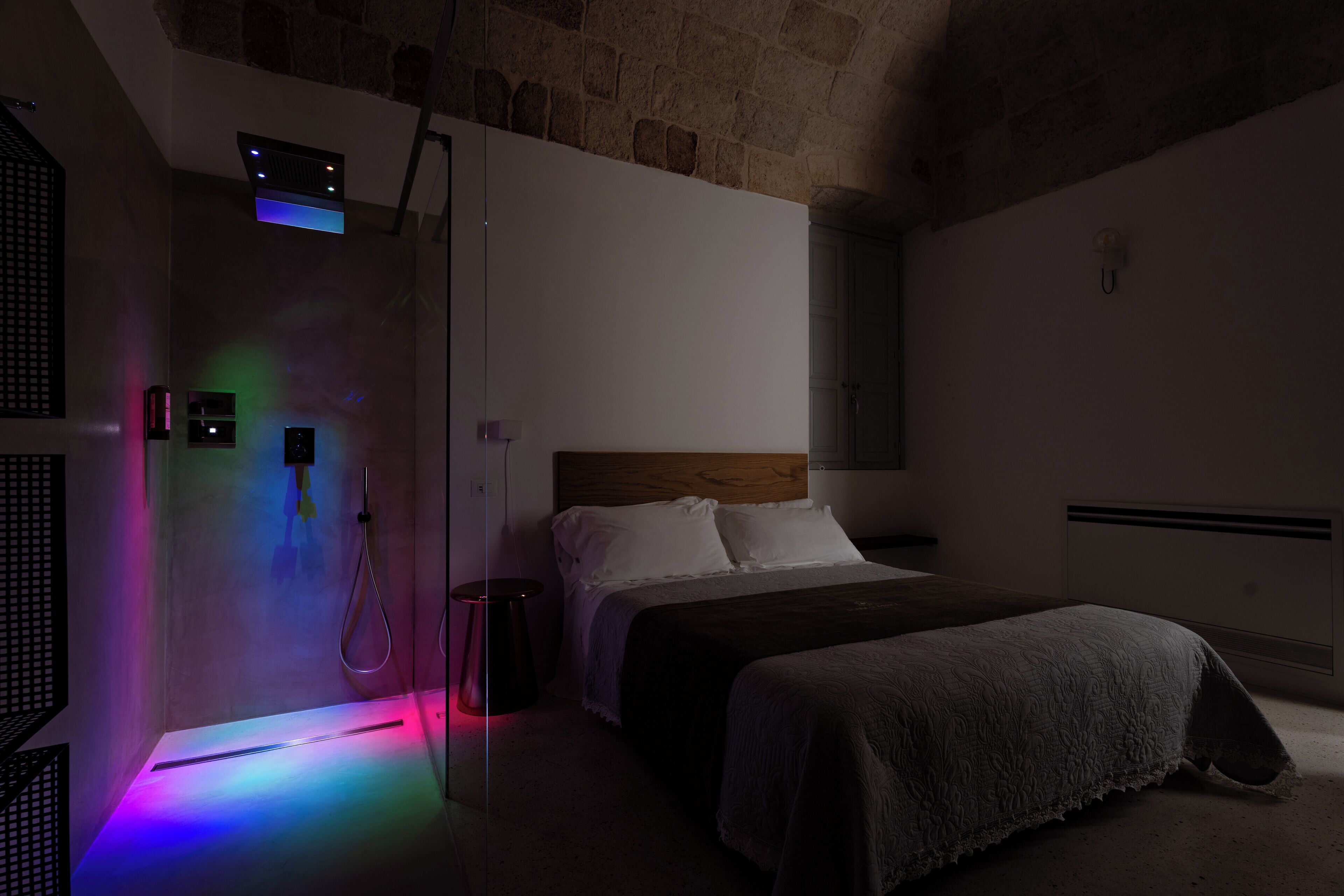 Una stanza poco illuminata con un letto, una doccia e un lampadario.