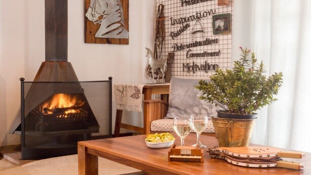 A cozy living room with a fireplace, a wooden table, a potted plant, and a wall with motivational quotes. - Mooigezicht (Clarens)