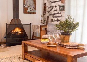 Una sala de estar acogedora con chimenea, una mesa de madera, una planta en maceta y una pared con citas inspiradoras.