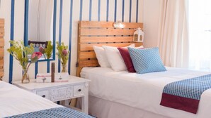 A hotel room with a wooden headboard, a bedside table with a lamp, and a bed with white bedding and colorful pillows. - Mooigezicht (Clarens)