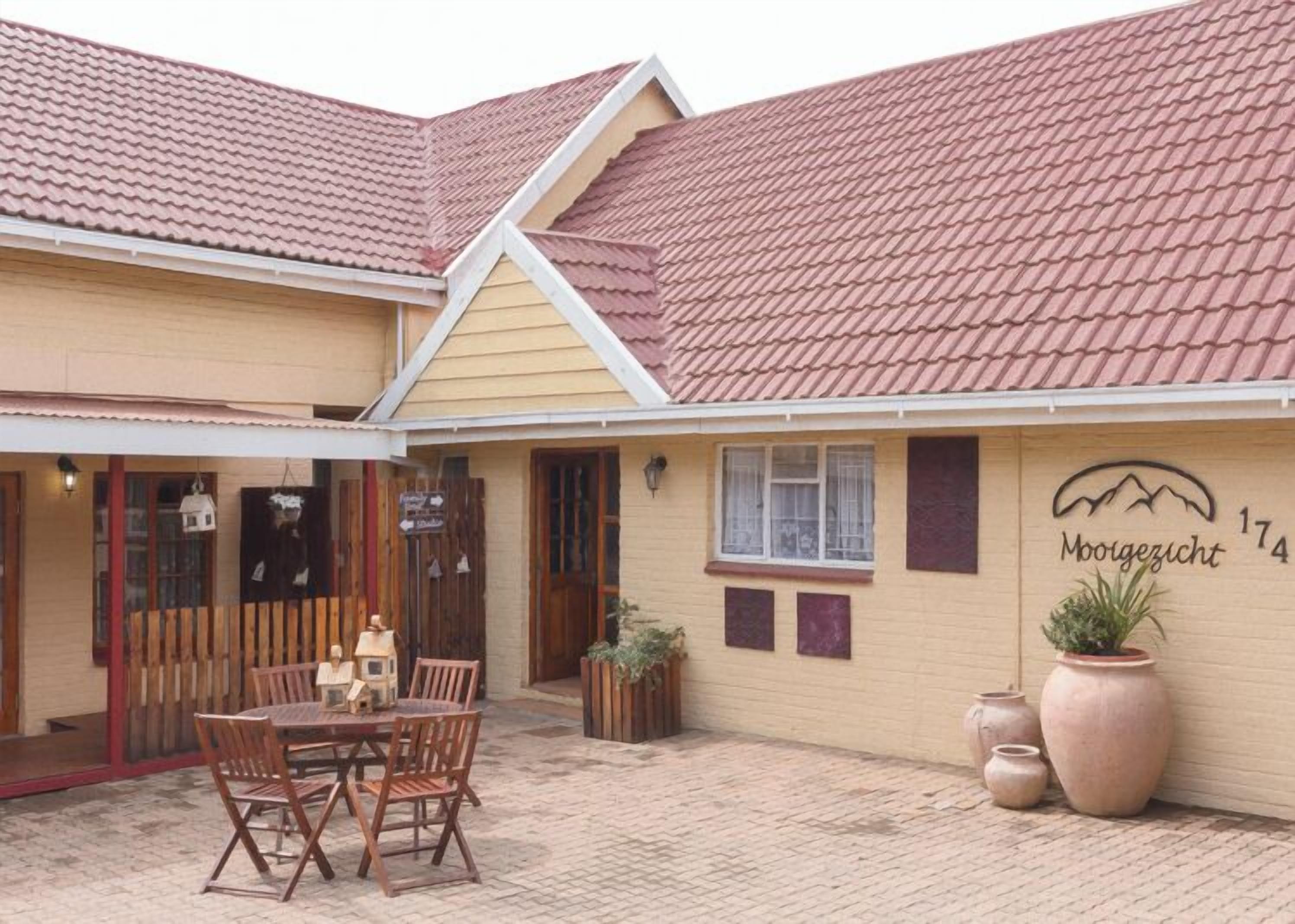 A building with a tiled roof, a sign reading 'Moorgezicht 174', and a patio area with a table and chairs.