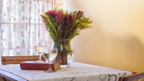 A table with a vase of flowers, two wine glasses, and a book. - Mooigezicht (Clarens)