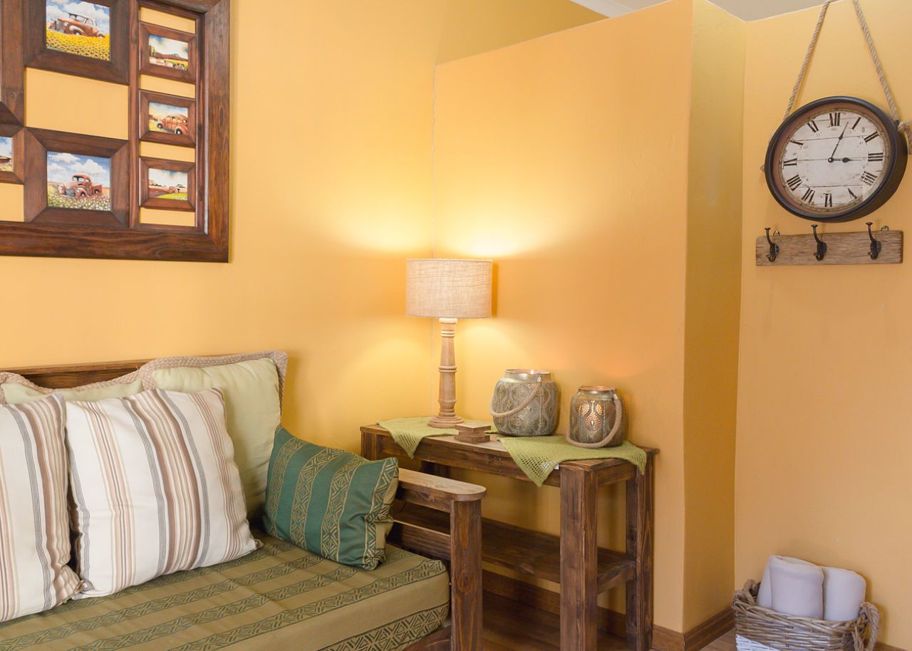 Una habitación acogedora con una cama de madera, una mesita con una lámpara y un reloj de pared.