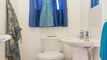 Un baño con inodoro, lavamanos y cortinas azules.