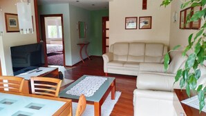 A living room with a TV, a sofa, a dining table, and chairs. - Apartament Królewski Sandomierz (Sandomierz)