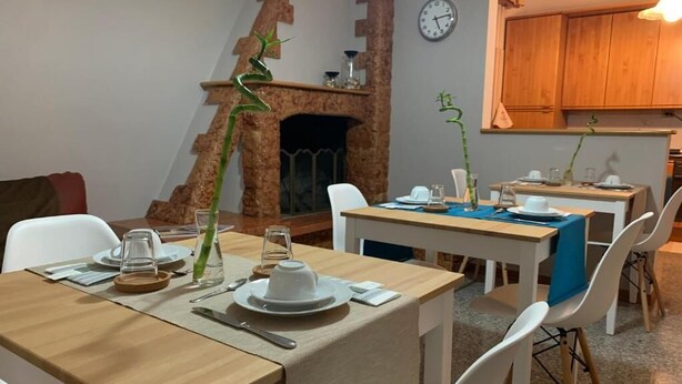 A dining area with wooden tables and chairs, a fireplace, and a clock on the wall. - Catarina (Tollo)