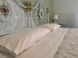 A bed with a white headboard and decorative floral patterns, a white pillow, and a patterned bedspread.
