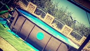 A swimming pool with a blue water feature, surrounded by a fence and a grassy area. - Catarina (Tollo)
