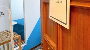 A wooden door with a sign reading "StanzaBlu" and a mirror reflecting a blue and white wall. - Catarina (Tollo)