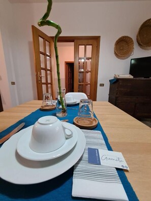 A dining table set with white plates, a white cup, and a glass pitcher, with a blue placemat and a card labeled 'Russo Giornata'.