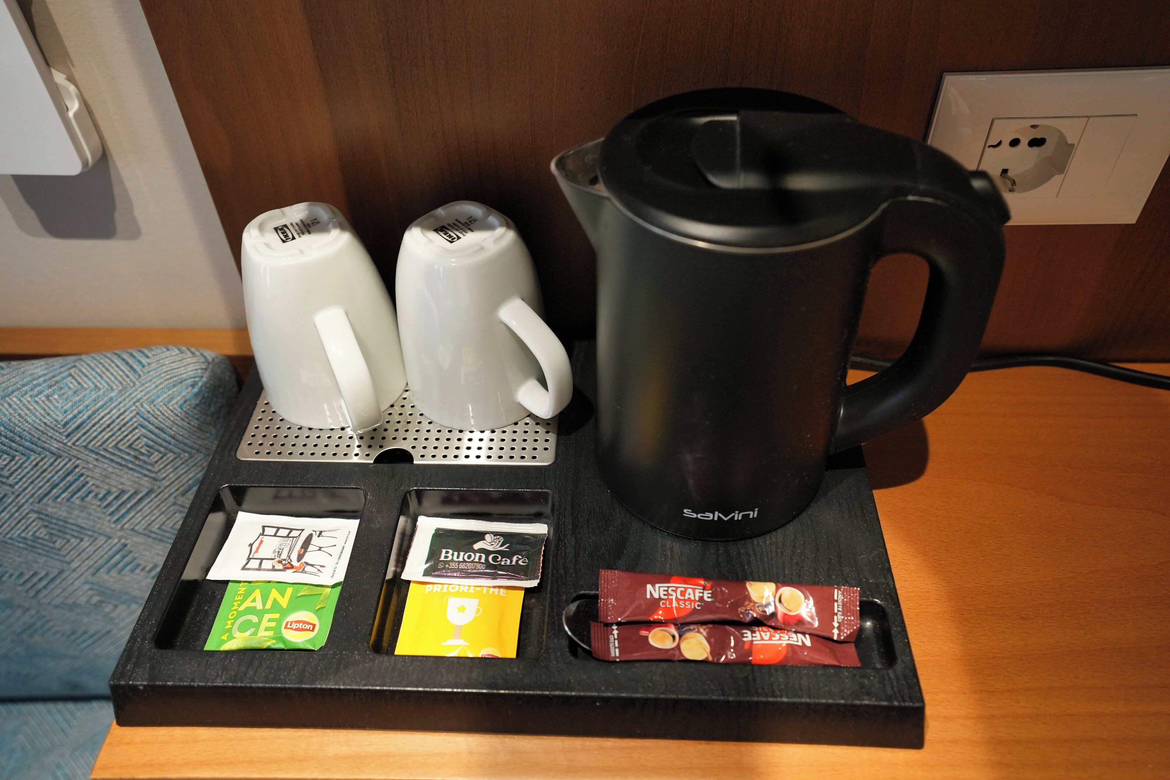 Un coin café comprenant une cafetière noire, deux machines à café blanches et plusieurs dosettes de café.