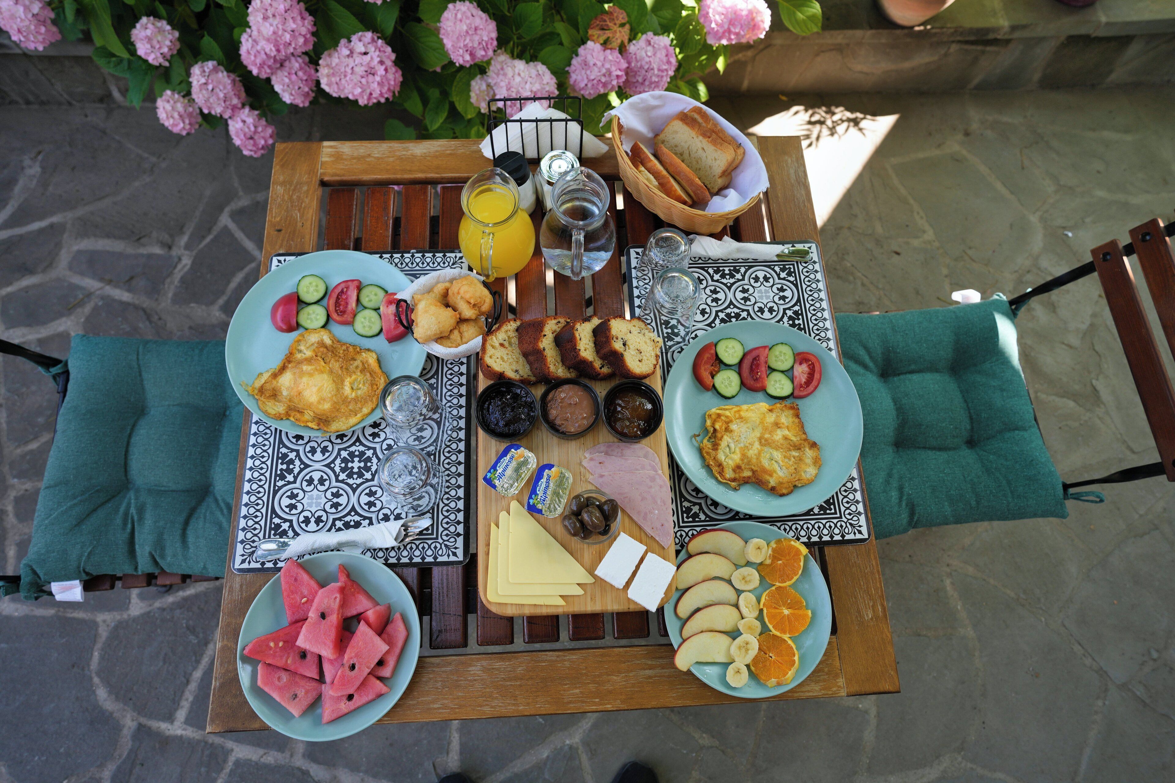 A table set with breakfast items including bread, fruit, and condiments.