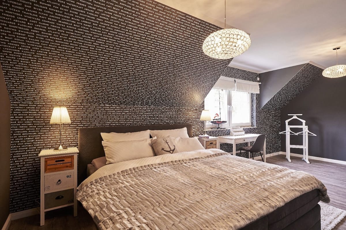 Un dormitorio con una cama grande, un escritorio y una lámpara colgante.