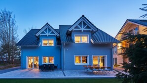 A two-story house with a blue exterior, a tiled roof, and a patio with outdoor furniture. - Freester Kapitänshäuser (Kröslin)