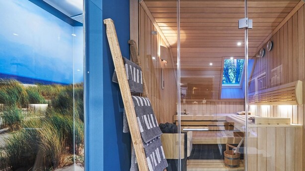 A sauna room with wooden benches, a glass partition, and a view of the outdoors. - Freester Kapitänshäuser (Kröslin)