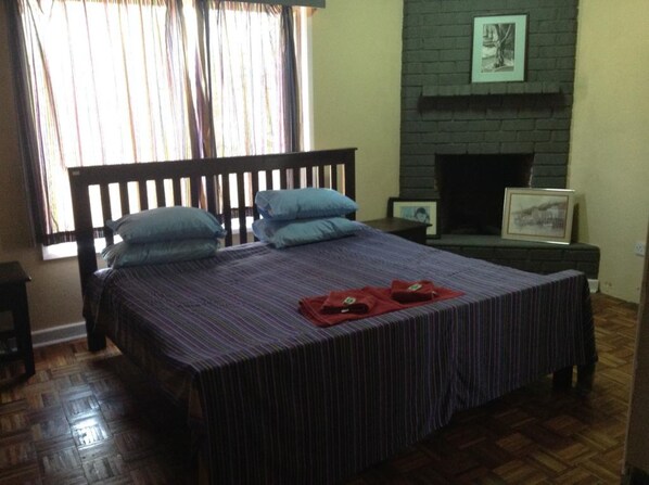 Un dormitorio con cama, chimenea y ventana con cortinas.