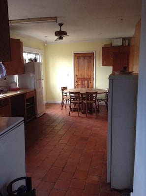 Una cocina compacta con una mesa de comedor, armarios de madera y piso de baldosas.