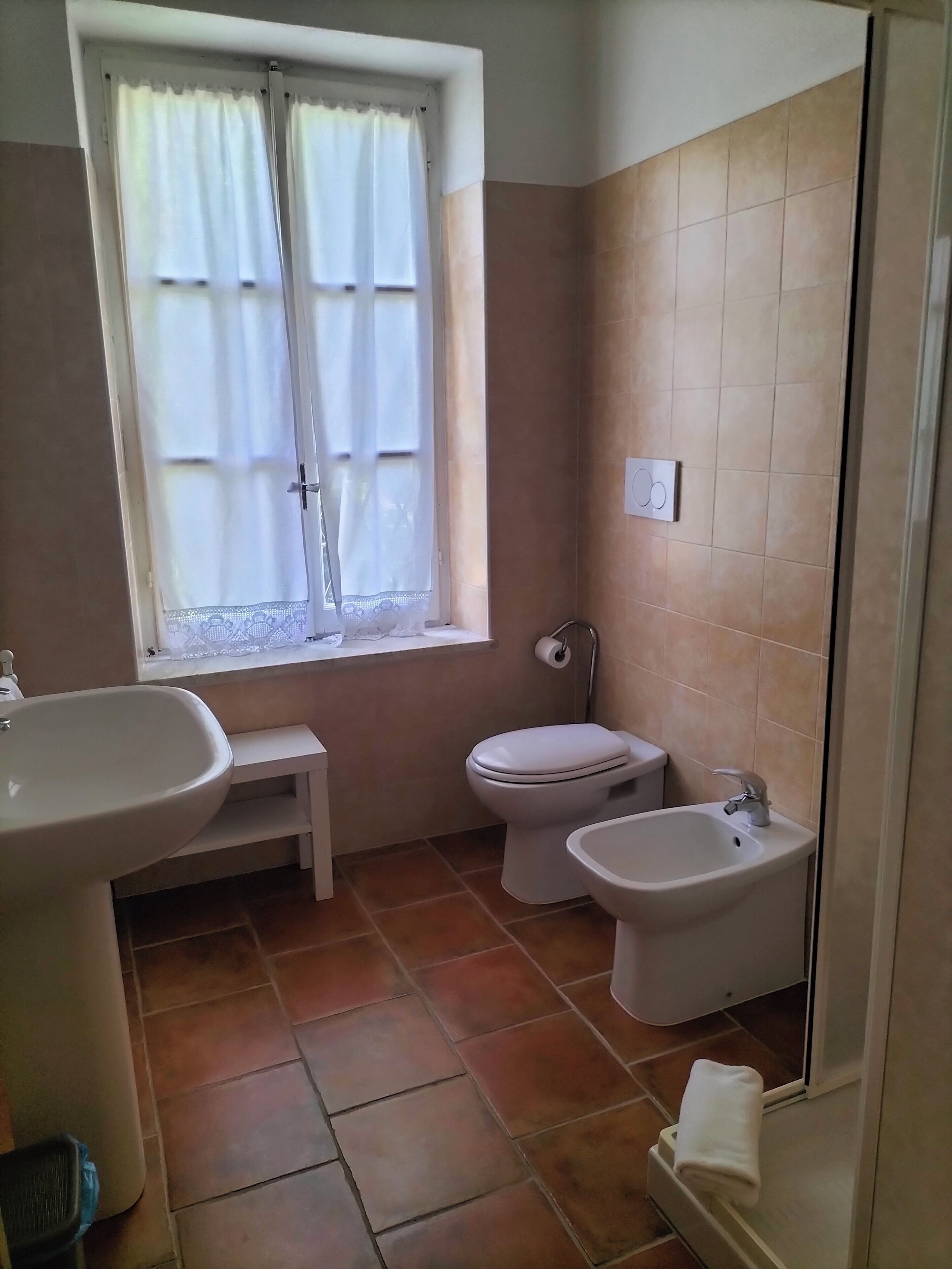 Un baño con lavamanos, inodoro, bidé y ventana con cortinas.