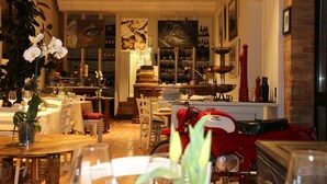 Un restaurante con mesas dispuestas para comer, una zona de bar con botellas y una motocicleta antigua.
