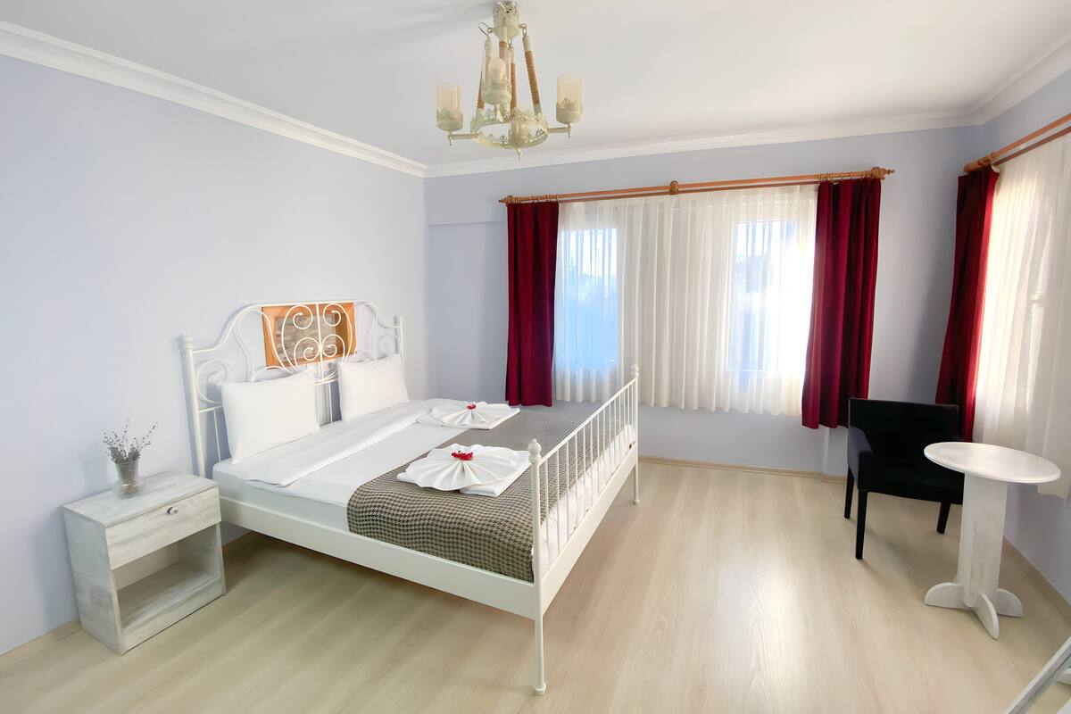 A bedroom with a bed, bedside table, chair, and a small table.