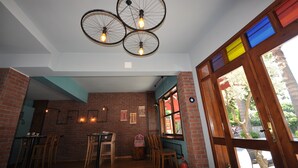 A restaurant interior with brick walls, wooden furniture, and a bicycle light fixture. - Queen Bee Hotel (Selçuk)
