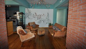 A living room with a large wall mural, wooden flooring, and a brick wall. - Queen Bee Hotel (Selçuk)