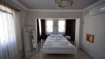 A neatly arranged bedroom with a metal bed frame, a wooden wardrobe, and a chandelier.