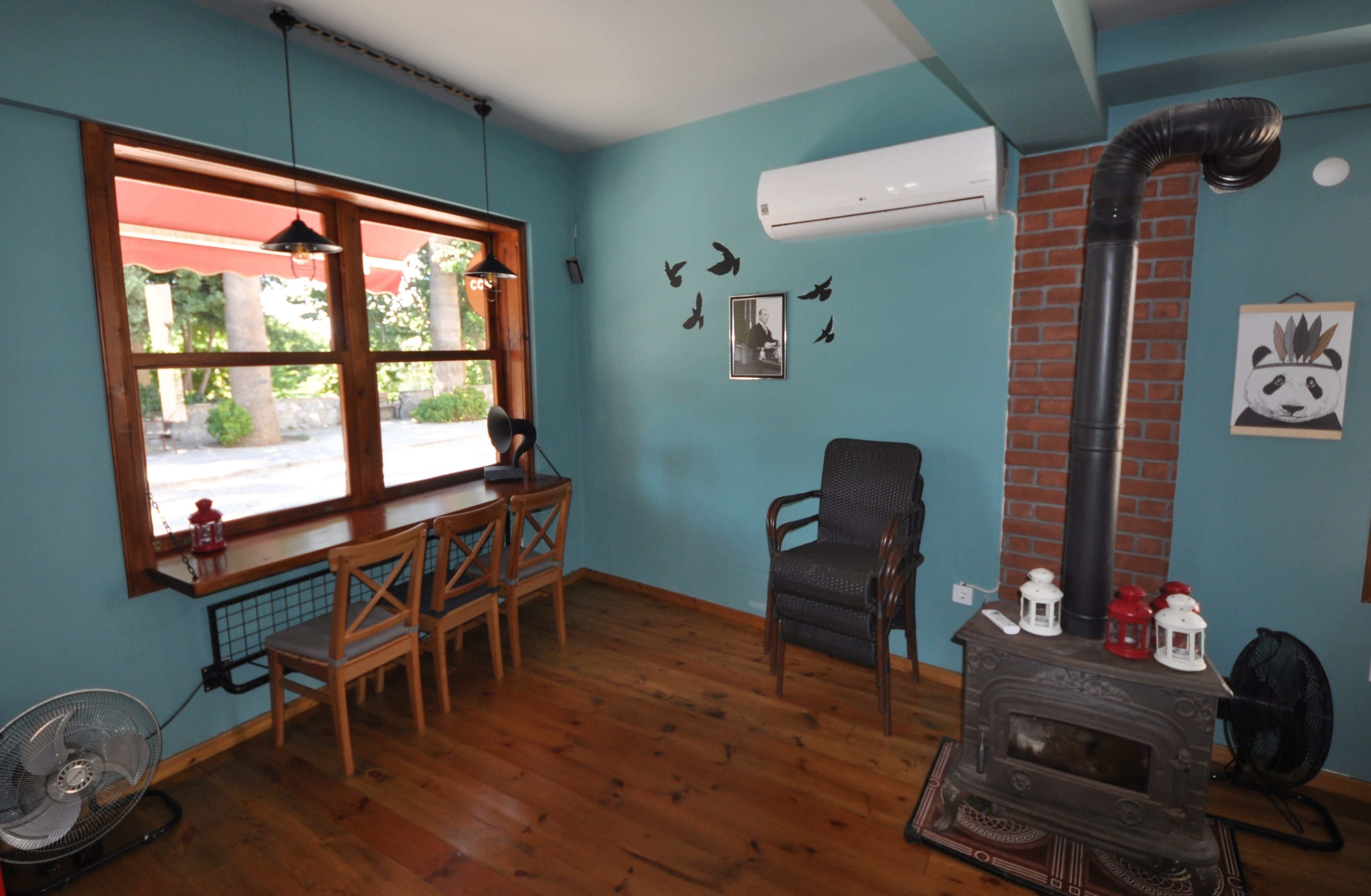 Una habitación acogedora con suelo de madera, ventana con vistas, chimenea y ventilador.